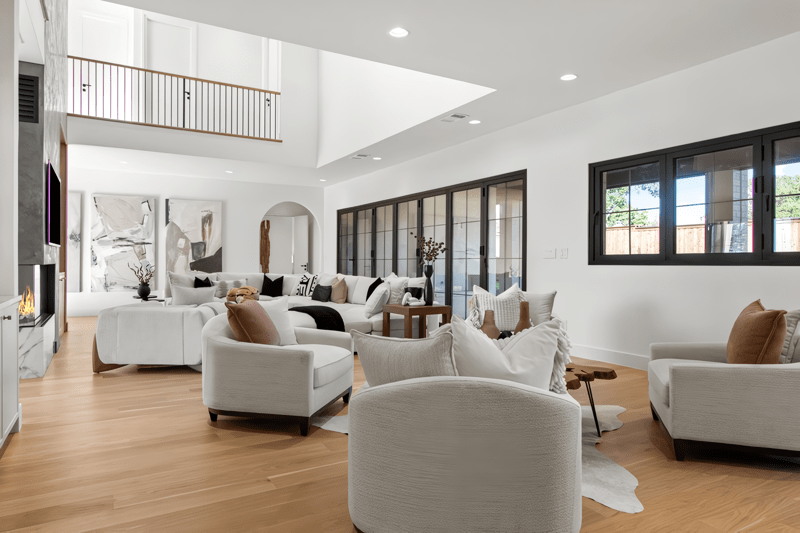 Bright, modern living room featuring stylish circular sofas, a wooden coffee table, and large windows. Art pieces adorn the walls, emphasizing contemporary design.