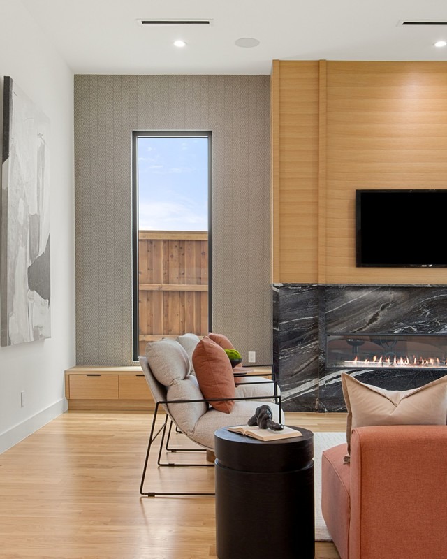 Modern living room featuring a sleek fireplace, large window, and stylish furniture in warm tones. Perfect for showcasing contemporary design.