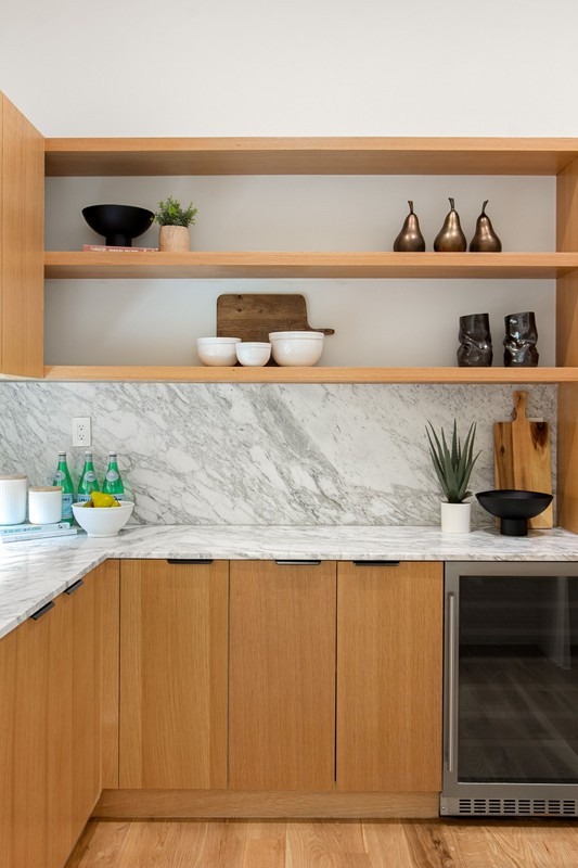 Modern kitchen featuring wooden cabinetry, marble countertop, and open shelves displaying decorative bowls and plants. Ideal for contemporary design inspiration.