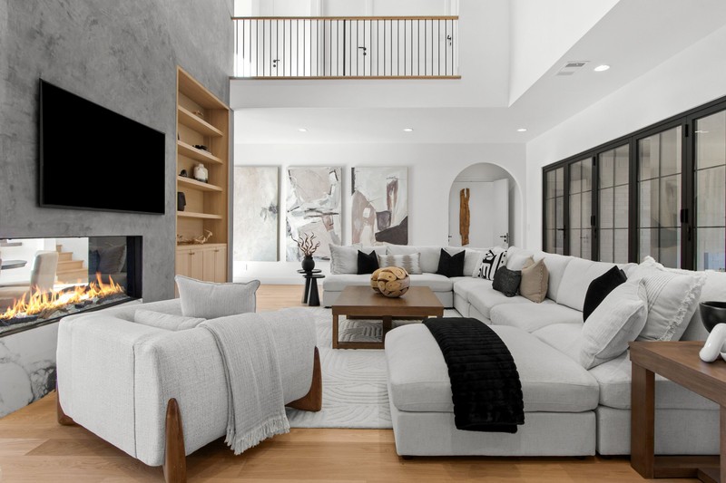 Modern living room featuring a spacious sectional sofa, a sleek fireplace, and artwork on the walls. Bright and inviting atmosphere.