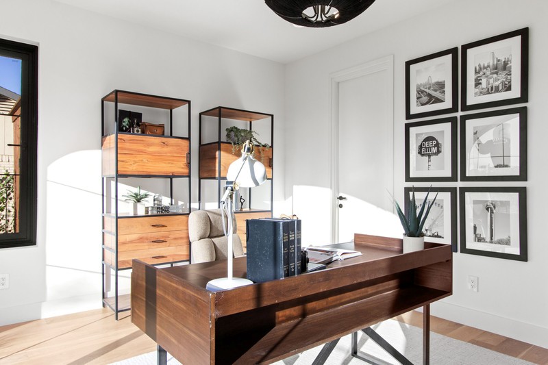 Bright and modern home office featuring a wooden desk, stylish shelving, and framed art, emphasizing a productive workspace.