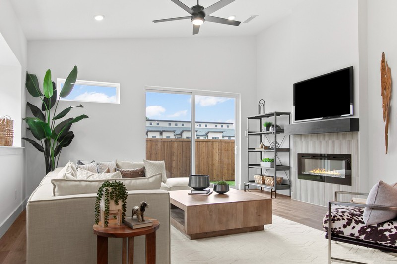 Bright, modern living room featuring a cozy sectional sofa, wooden coffee table, and a sleek fireplace. Large windows provide natural light and outdoor views.