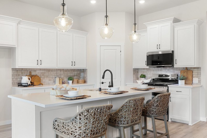 Modern kitchen featuring white cabinets, a spacious island with bar seating, and pendant lighting. Ideal for stylish home design inspiration.