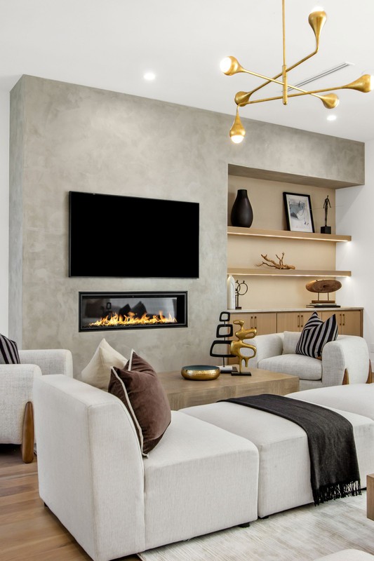 Modern living room featuring a minimalist design, a wall-mounted television, a linear fireplace, and sleek furnishings with a cozy atmosphere.