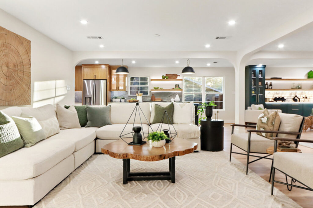 Modern living room featuring a spacious sectional sofa adorned with green and neutral pillows, a rustic wood coffee table, and a stylish decor.