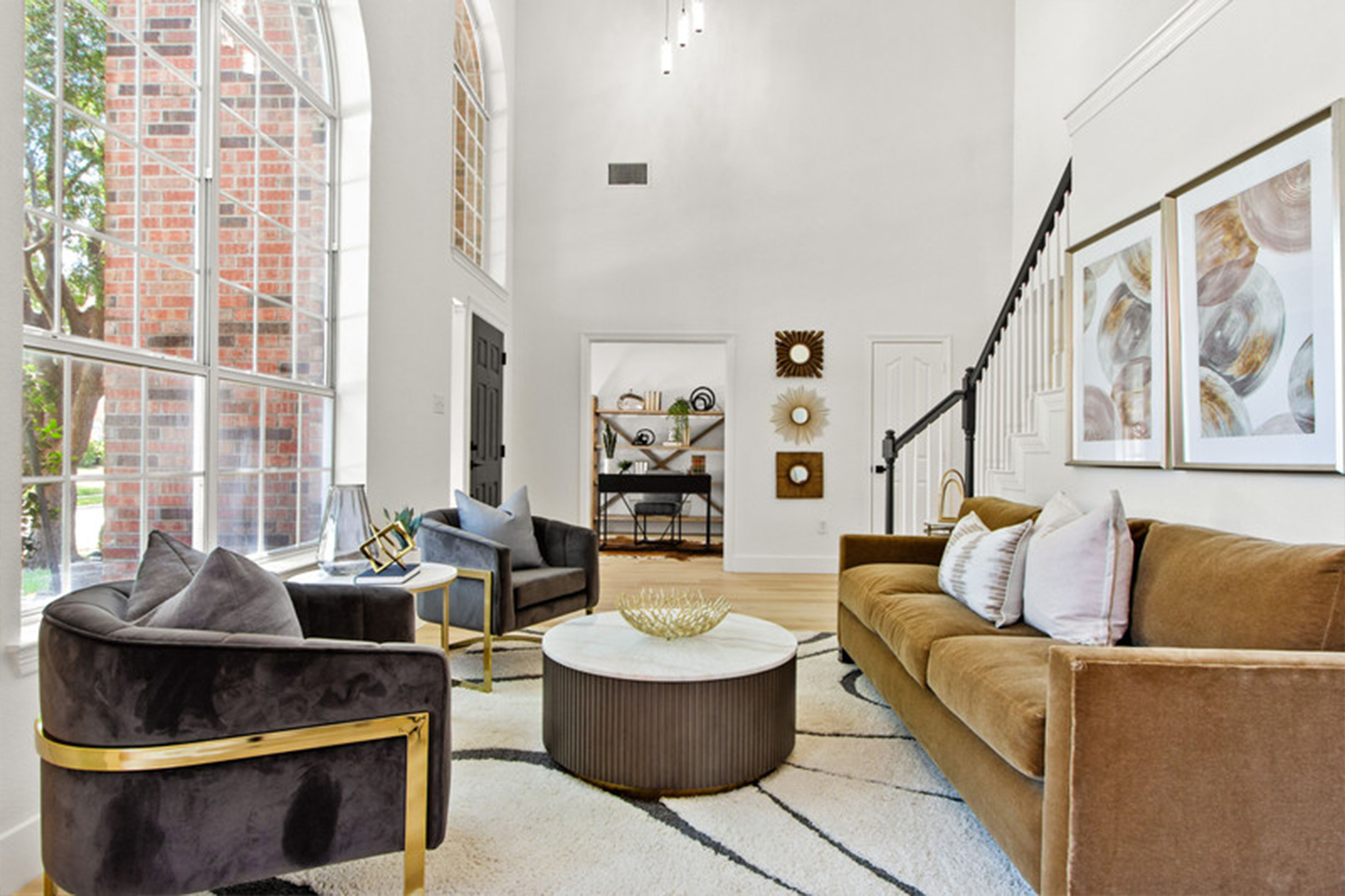 Spacious, modern living room with high ceilings, large windows, and elegant furniture. Natural light highlights decorative elements and a cozy ambiance.