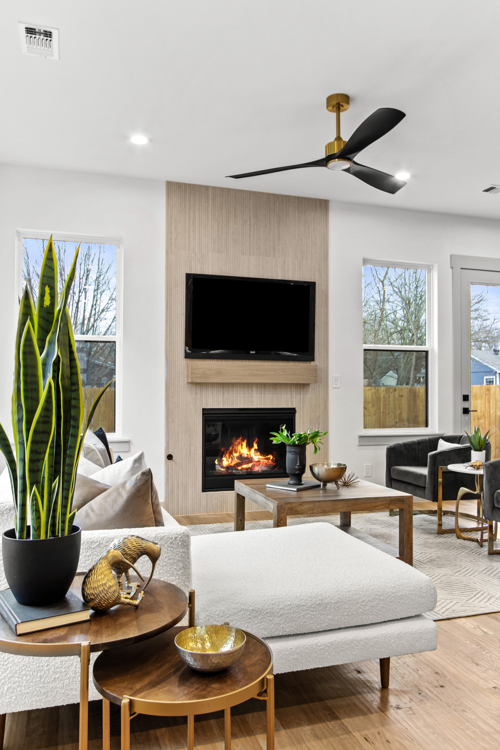 Modern living room featuring a sleek gray sofa, large potted plant, decorative tables, and a cozy fireplace, perfect for relaxation and gatherings.