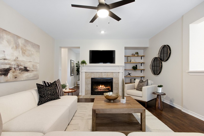 Cozy living room featuring a white sectional sofa, wooden coffee table, and a fireplace. A TV is mounted above the mantle, enhancing the inviting atmosphere.