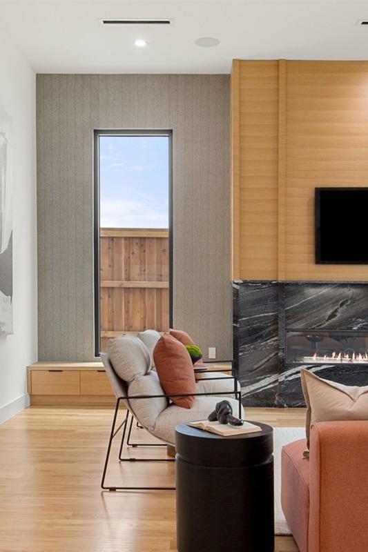 Modern living room featuring a sleek fireplace, large window, and stylish furniture in warm tones. Perfect for showcasing contemporary design.
